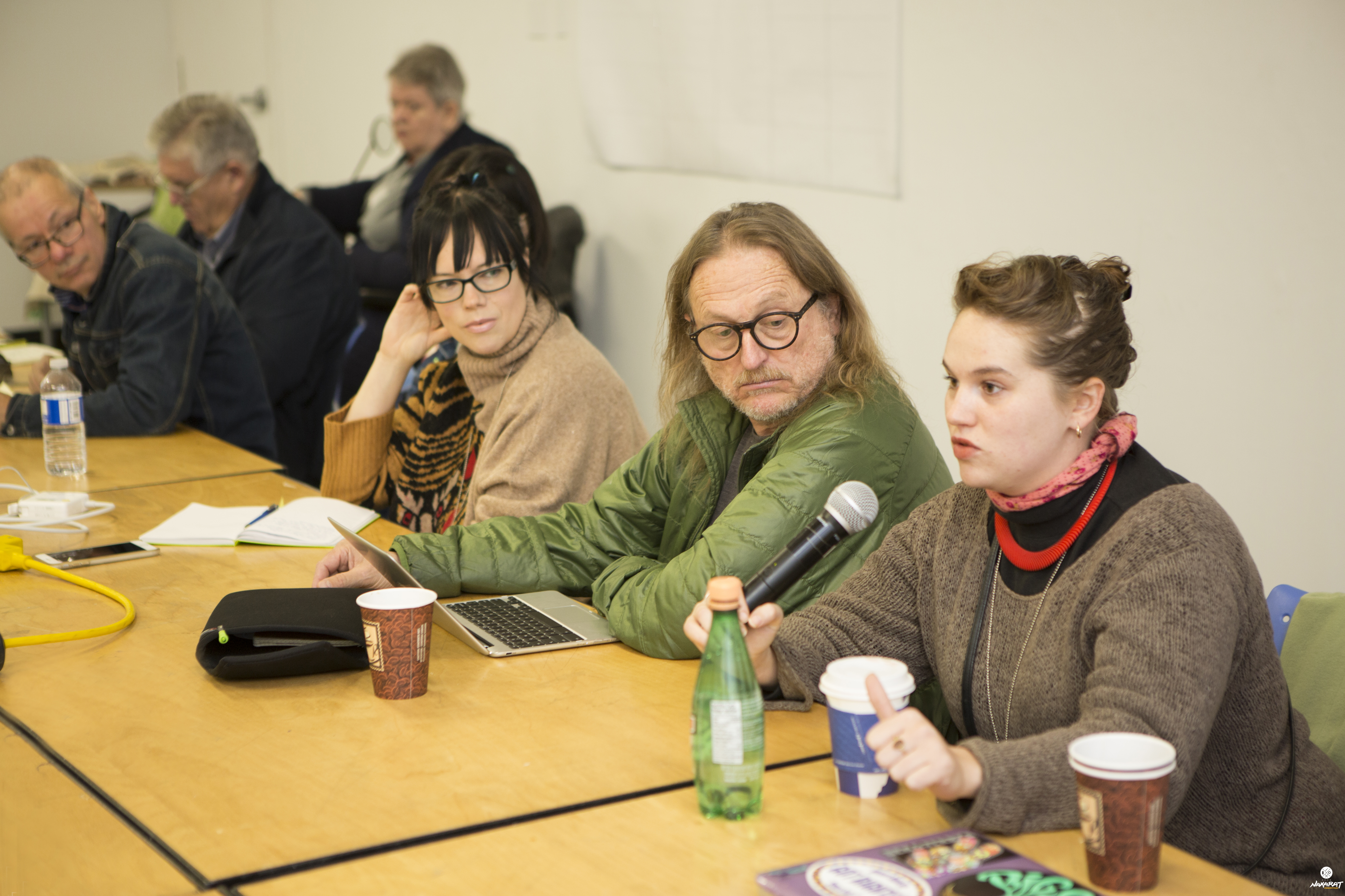 Six individuals wearing at a conference table. Having a discussion and looking aty the speaker on the far right
