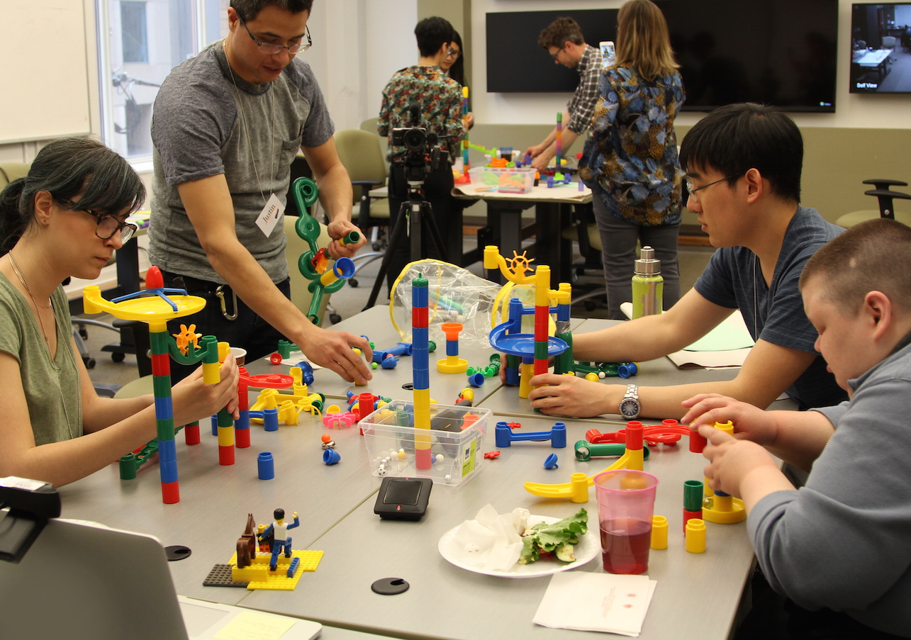 Group of four people making a 3D prototype with plastic lego blocks.